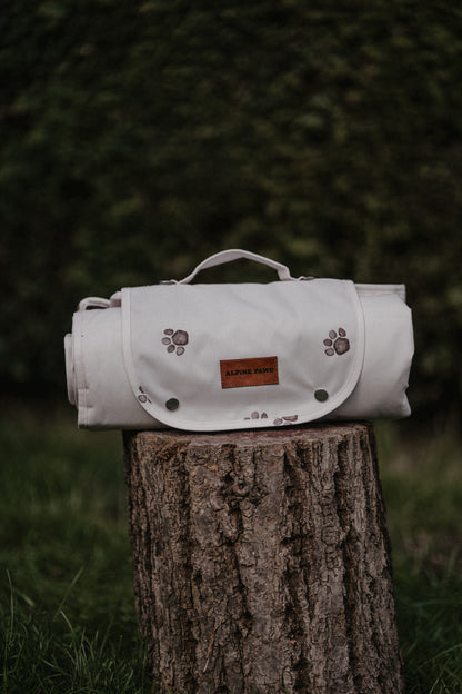 White pet travel mat with paw prints on a tree stump against a green background