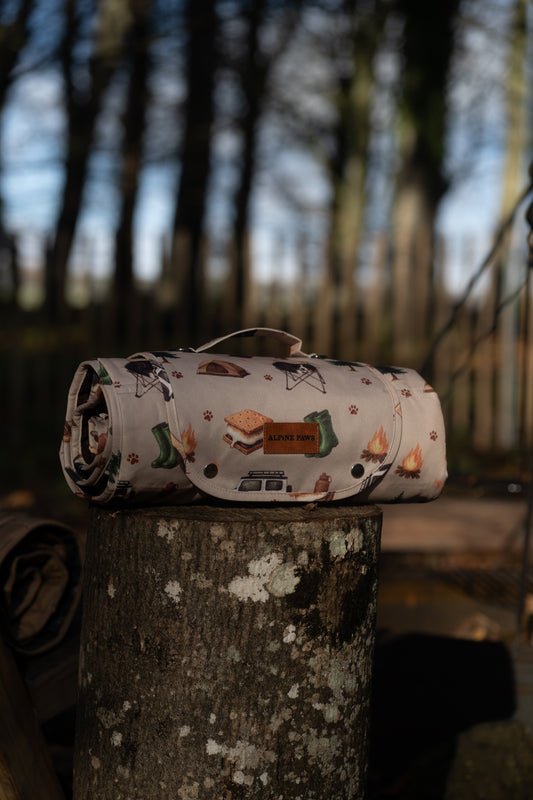 Roll-up mat with camping-themed design on a tree stump in a forest setting