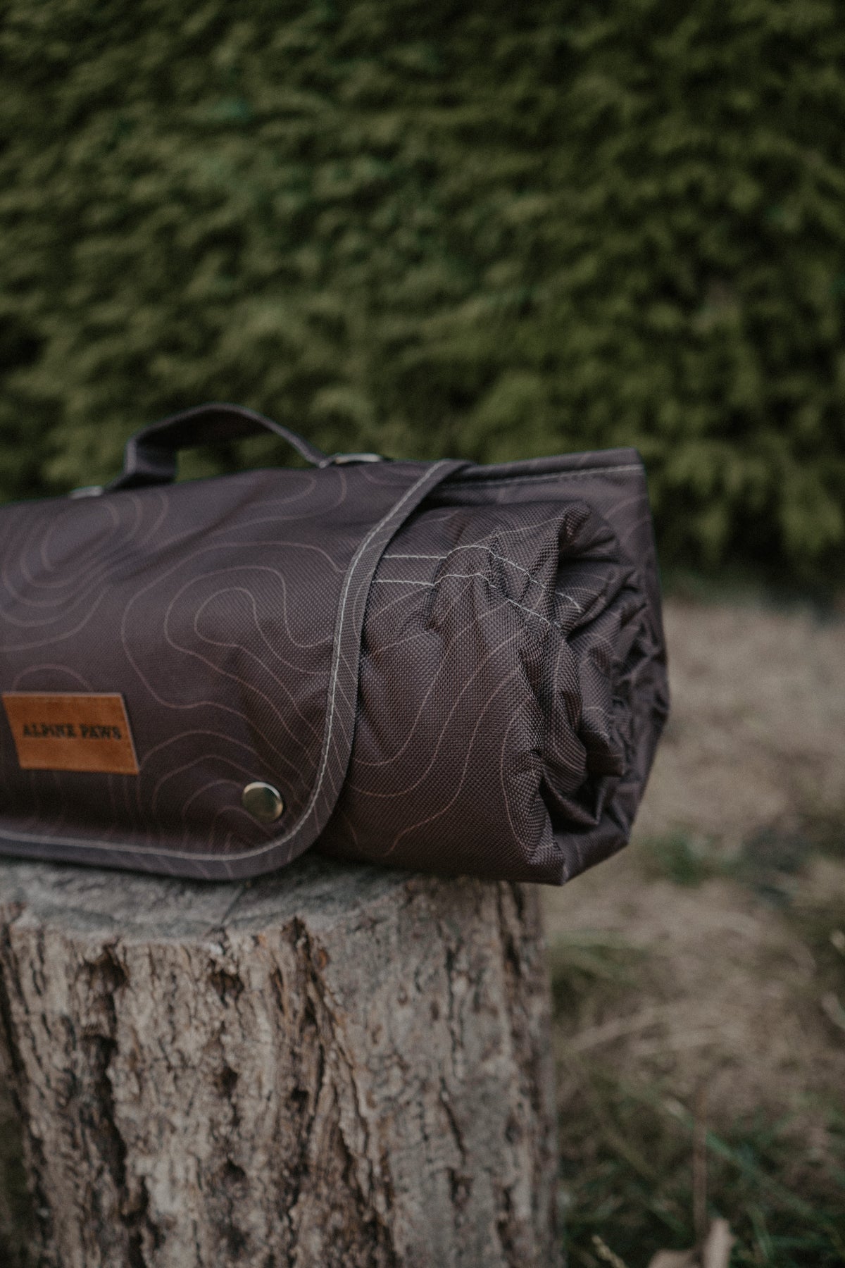 A rolled dark brown settle dog mat with a topographic contour line pattern 